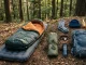 Schlafsack, Isomatte, Tarp und wichtige Ausrüstung liegen auf einer Waldlichtung.