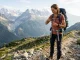 Wanderin optimiert die Passform von Rucksackriemen an einem Trekkingrucksack auf einem Bergpfad.