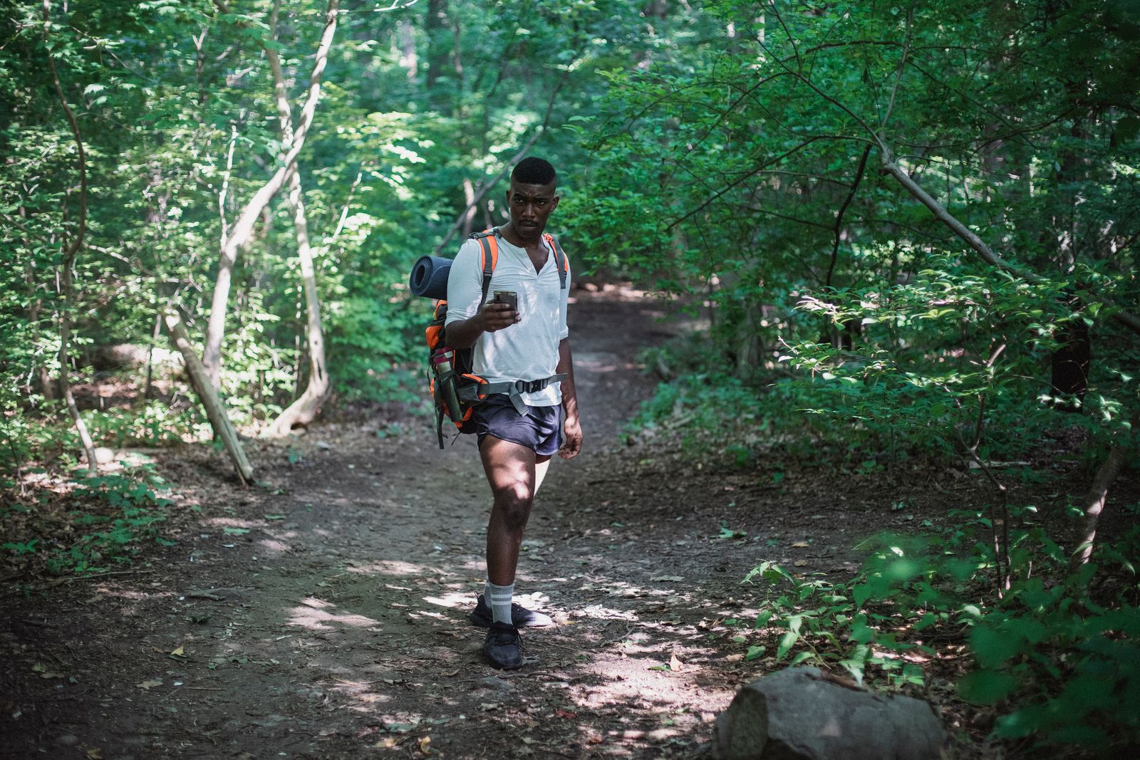 Wanderer mit Rucksack sucht im Wald auf dem Smartphone nach der Route