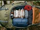 Geöffneter Wanderrucksack mit Schlafsack im Bodenfach und geordneter Ausrüstung im Hauptfach.