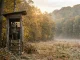 Jäger auf einer Kanzel beim Ansitz im Herbst an einer herbstlichen Äsungsfläche.