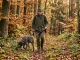 Jäger führt seinen Jagdhund während einer Brauchbarkeitsprüfung auf einer Fährte durch den Wald.