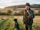 Falkner bei der Falknerei-Beizjagd mit Wanderfalke auf dem Handschuh und Jagdhund im herbstlichen Revier.