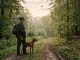 Jäger und Jagdhund im Wald bei Tollwut in Deutschland, mit Rotfuchs in der Ferne.